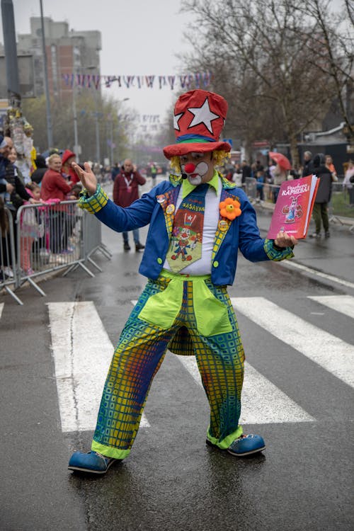 A Clown with Red Nose and Colorful Costume Standing on the Street