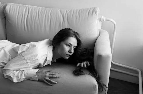A Woman in White Long Sleeves Lying Down on the Couch