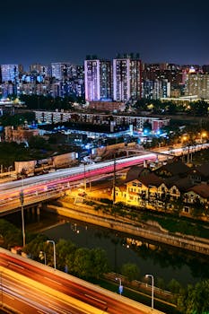 北京高速公路的夜景中，有发光的摩天大楼和灯光条纹
