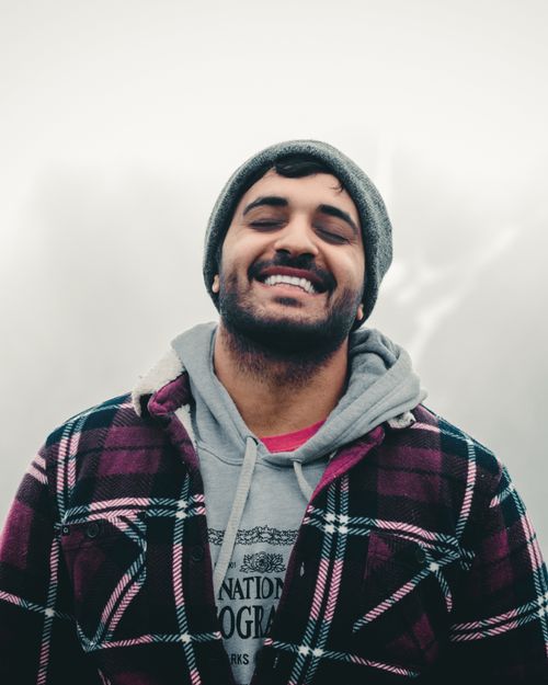 Free Young man with closed eyes smiling in winter clothing, expressing happiness. Stock Photo