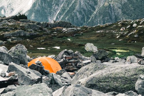 Free Orange tent nestled among rocky peaks in British Columbia's outdoor wilderness. Stock Photo