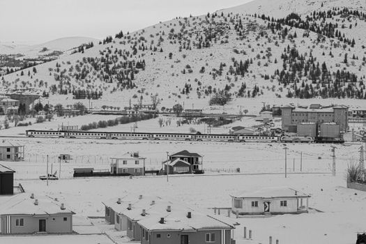 Black and white photo of a train passing through a snowy landscape in Ulukışla, Turkey.