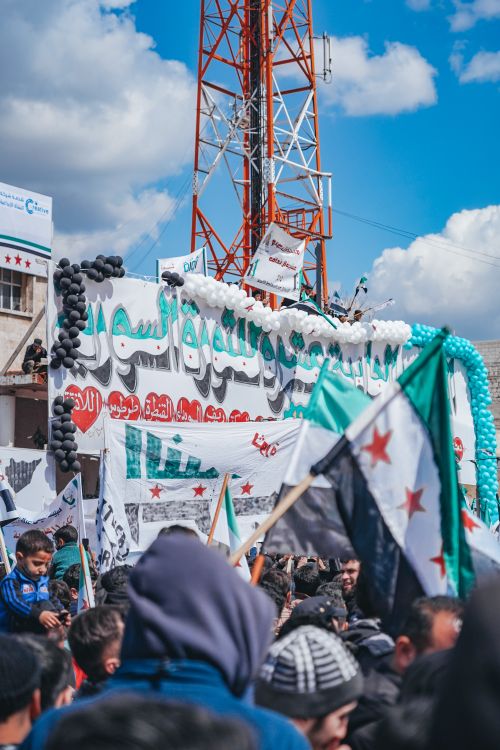 Free Protesters in Syria waving flags and banners under a clear blue sky. Stock Photo