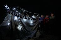 Joyful children by illuminated Ramadan tent in Idlib, Syria, at night.