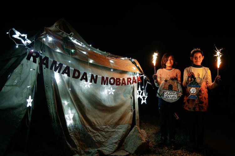 Girls Standing Near The Tent While Holding A Sparklers At Night