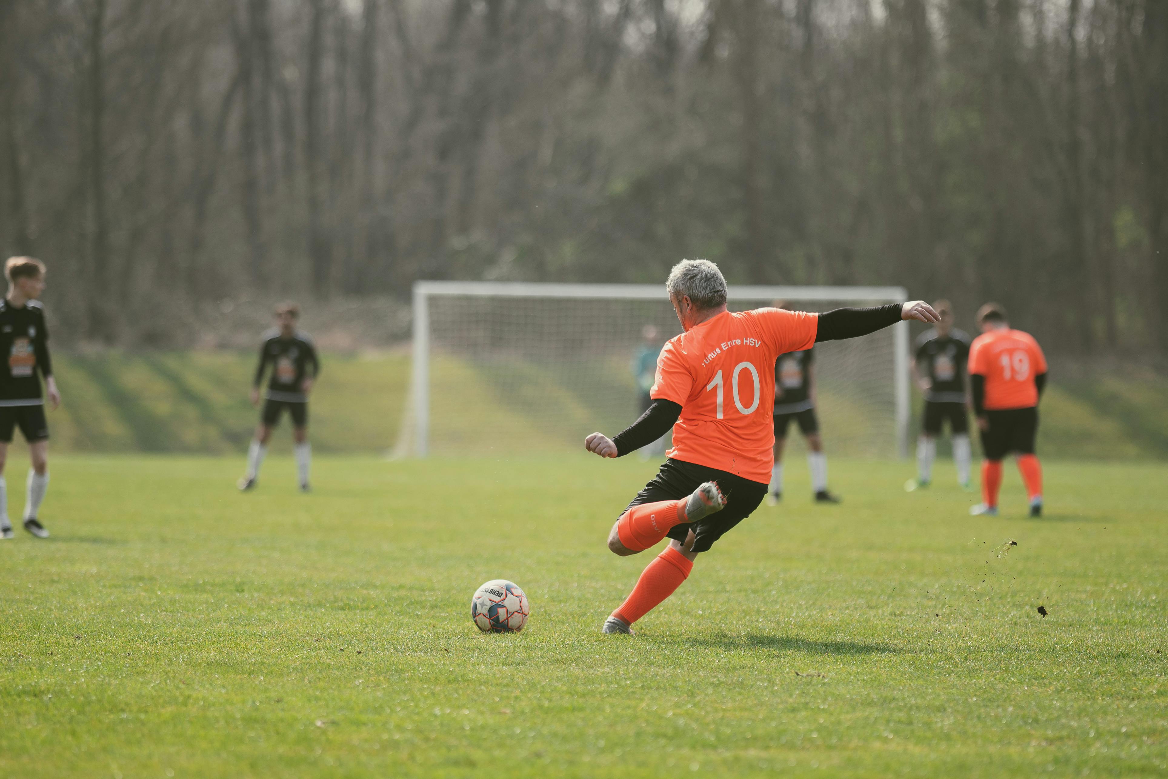 a man in soccer jersey kicking a ball on the field