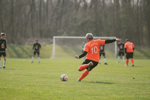 Free A Man in Soccer Jersey Kicking a Ball on the Field Stock Photo