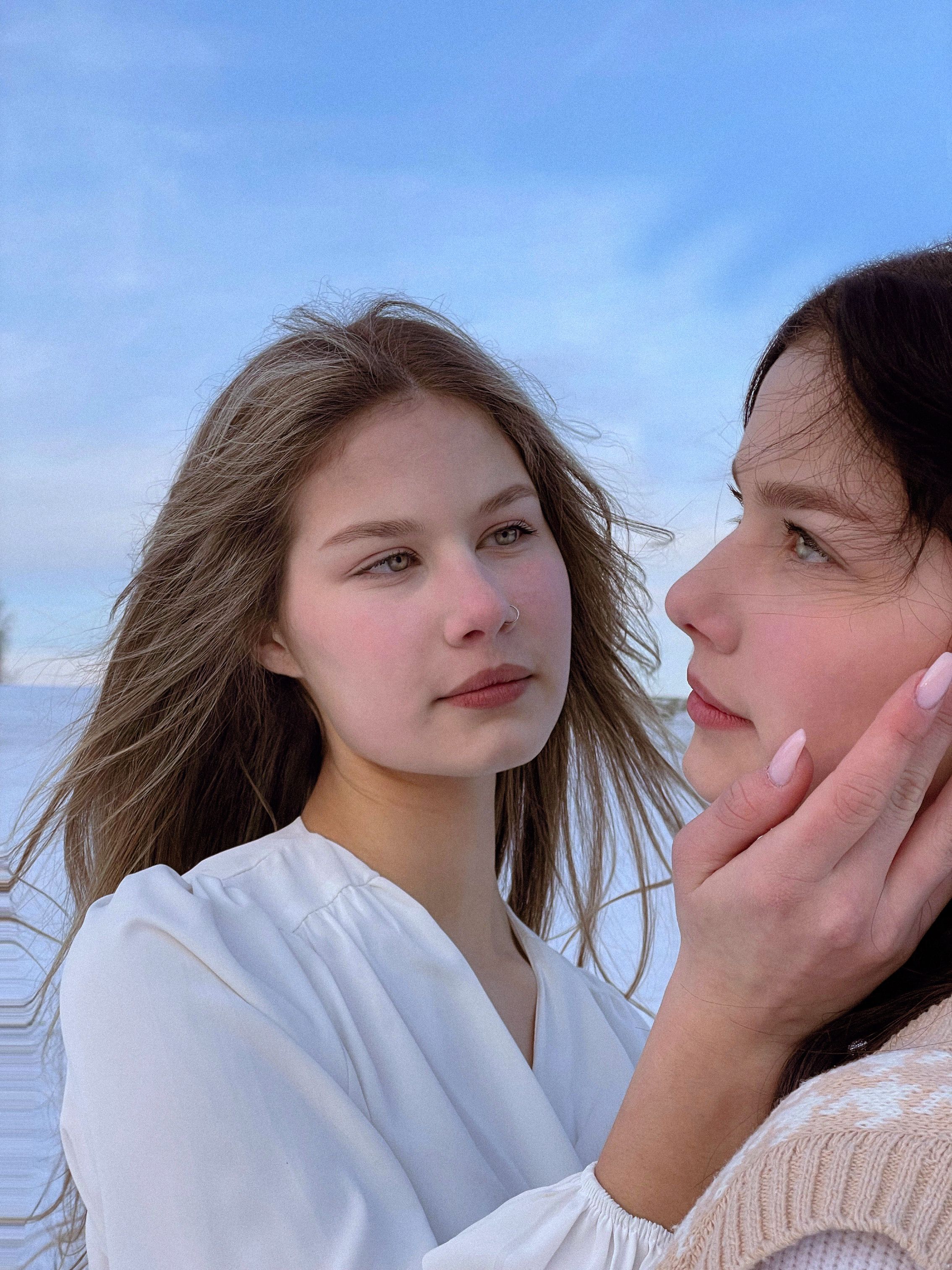 Close-up portrait of two women in Belarus with a serene blue sky background.