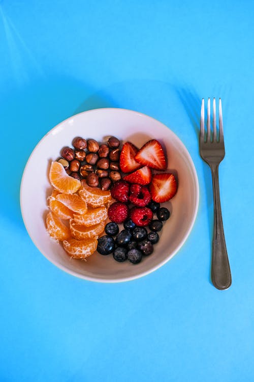 Variety of Fruits on White Ceramic Bowl With Gray Fork