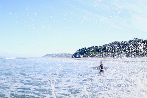 Free Person Carrying Surfboard Walking on Sea Water Stock Photo
