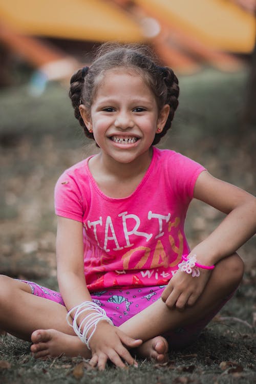 A Young Girl in Pink Shirt Sitting on the Grass