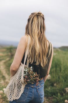 Woman with blonde hair holding eco-friendly bag with flowers outdoors.