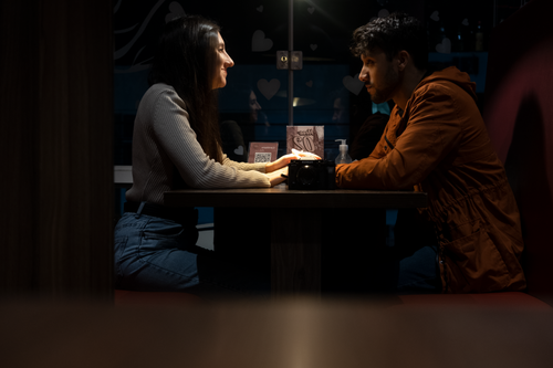 Free A couple sitting face-to-face, enjoying a romantic evening indoors with intimate lighting. Stock Photo