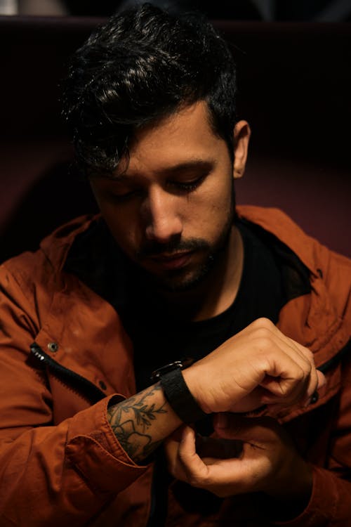 A Man in Brown Jacket Looking at His Watch