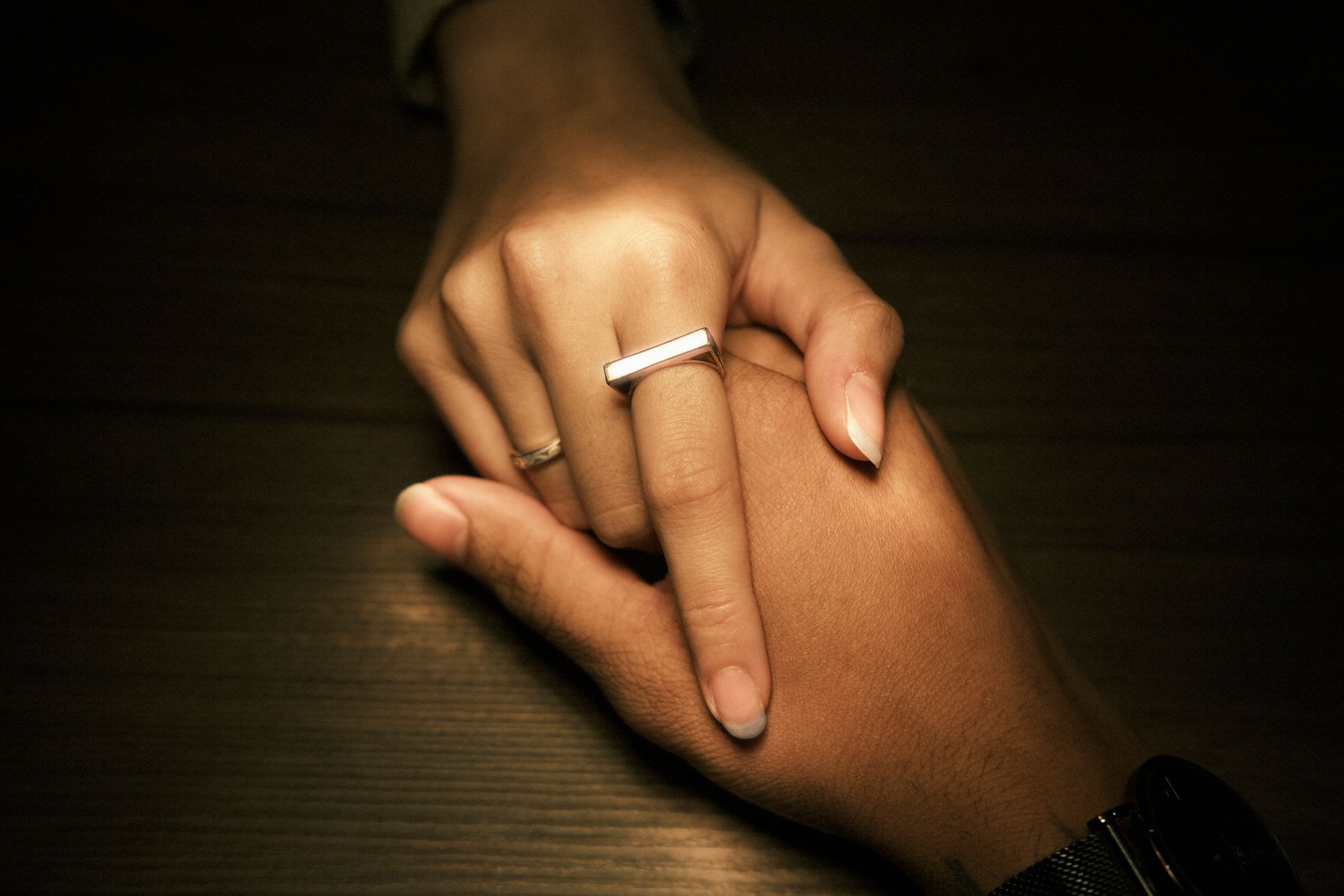 Close-up of a couple holding hands, highlighting rings and affection.