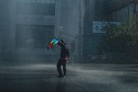 A lone protester holding a flag on a rainy street, symbolizing activism and resilience in Valparaíso, Chile.