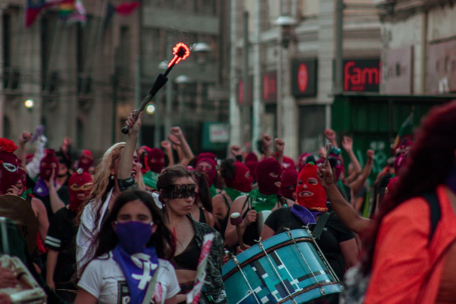 Mujeres empoderadas marchando con tambores y máscaras en el evento callejero de Valparaíso.