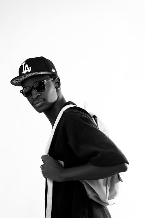 A Grayscale Photo of a Man in Black Shirt Wearing Sunglasses and a Cap