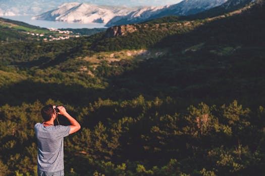 一名男子白天用双筒望远镜欣赏山区的优美风景