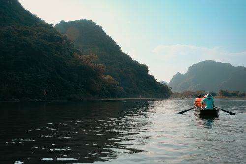 Free Capture of people rowing on a scenic lake surrounded by mountains under a clear sky. Stock Photo