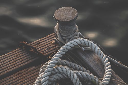 Free A close-up of a wooden dock with coiled rope and bollard, capturing maritime vibes. Stock Photo