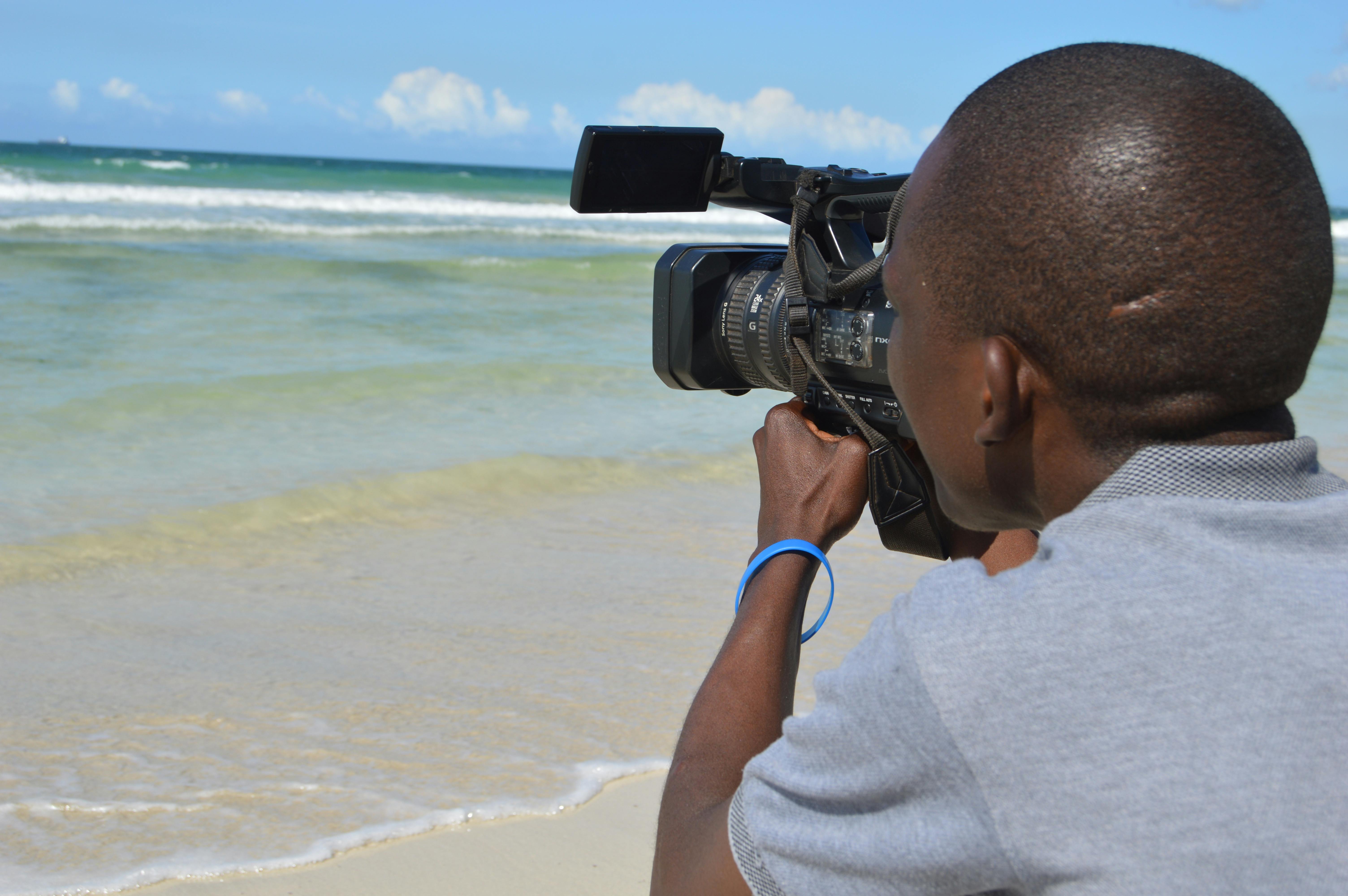 a man filming on the beach