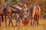 A Couple Standing on the Field Near the Brown Horses