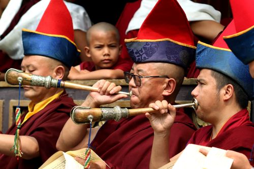 Free Monks in colorful attire playing traditional Tibetan horns during a cultural ceremony. Stock Photo