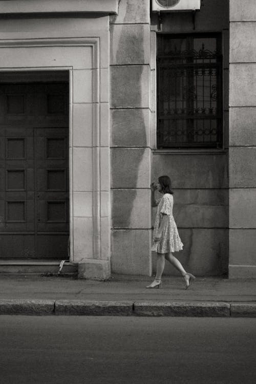 Free A Grayscale Photo of a Woman in White Dress Walking on the Street Stock Photo