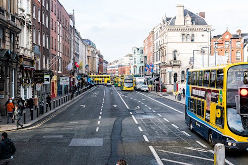 People Walking on the Street Near the Road with Moving Buses