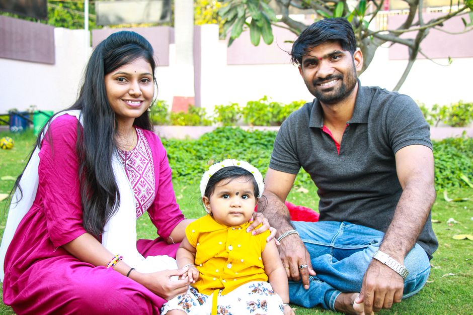 How to Use the DIME Method to Calculate Life Insurance Coverage A happy family with parents and a toddler enjoying quality time sitting on a grassy lawn outdoors.