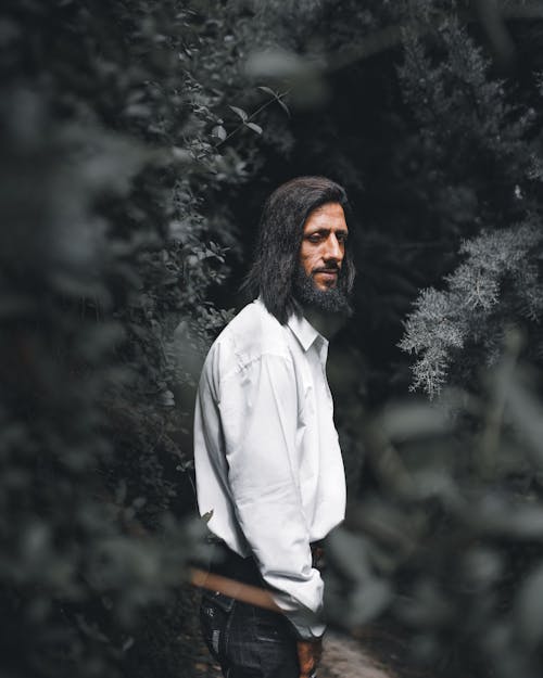 A Bearded Man in White Long Sleeves Standing Near the Trees
