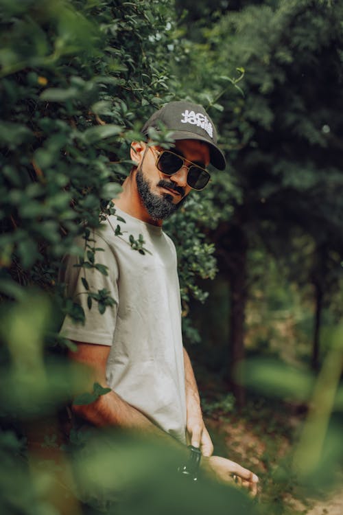 Man in T-shirt Standing Beside the Plants