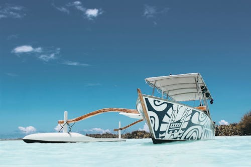 White and Blue Wooden Canoe Under Blue Sky at Daytime