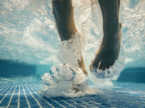 Underwater view of feet splashing in a swimming pool, creating bubbles and waves.