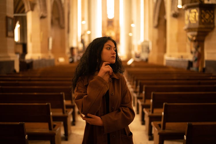 A Woman In Brown Coat Standing On The Aisle