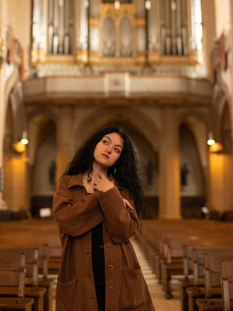 A Woman In Brown Coat Standing On The Aisle