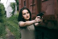 caucasian girl hold a gun. military girl. green t-shirt.