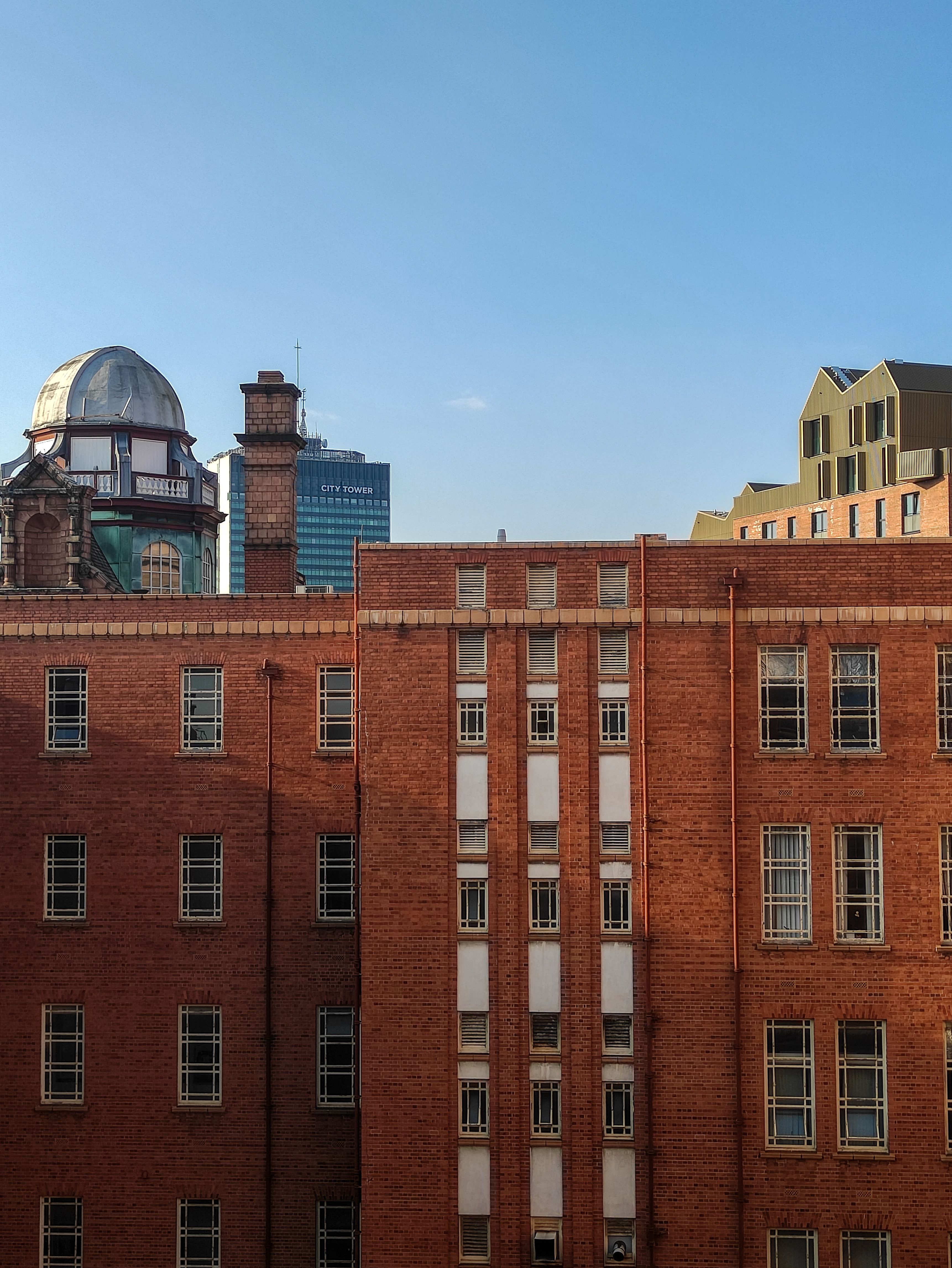 Brown Brick Building with Glass Window Under Blue Sky · Free Stock Photo