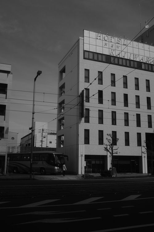 Free Black and white urban scene featuring a parked bus and a city hotel. Stock Photo