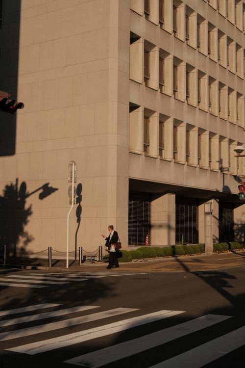Free Businessman walking in pedestrian lane next to modern office building during sunrise in the city. Stock Photo