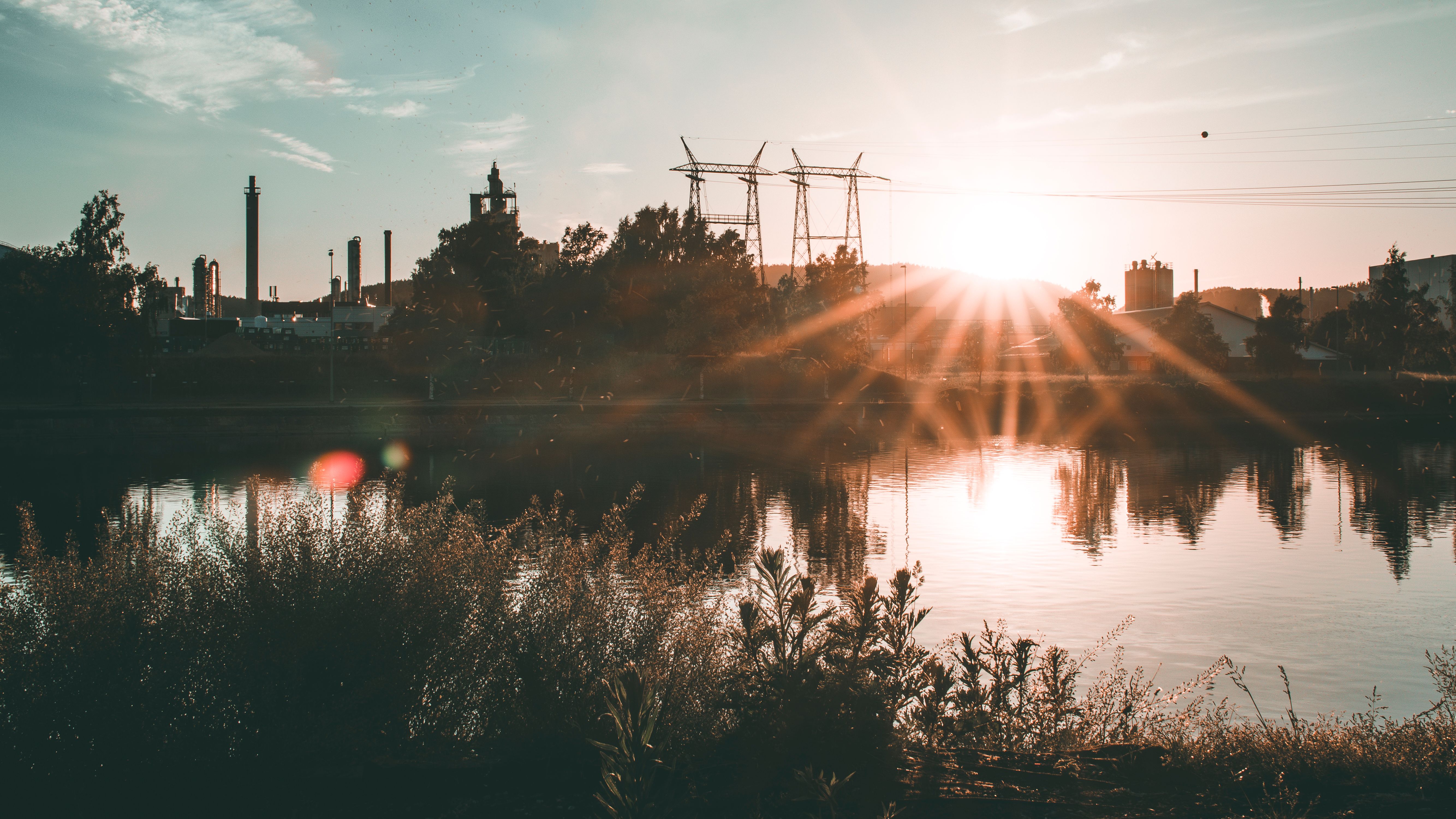 A captivating sunset over an industrial skyline reflected in a tranquil water body.