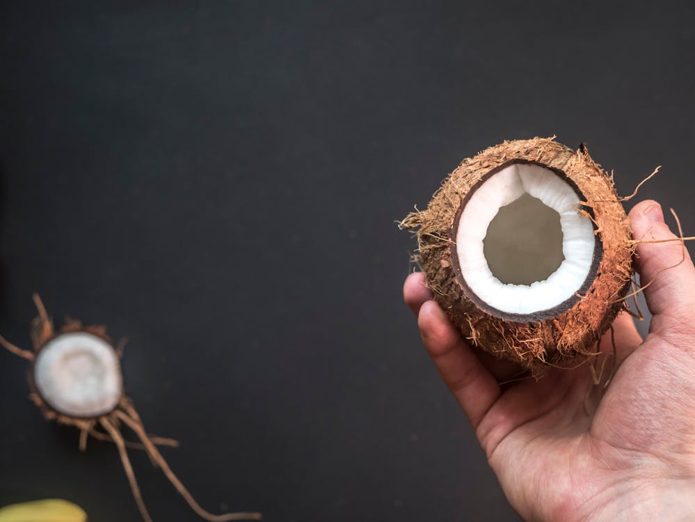 Glass jar of pure coconut oil with fresh coconut pieces — a natural source of MCTs ideal for boosting ketosis on the keto diet.
