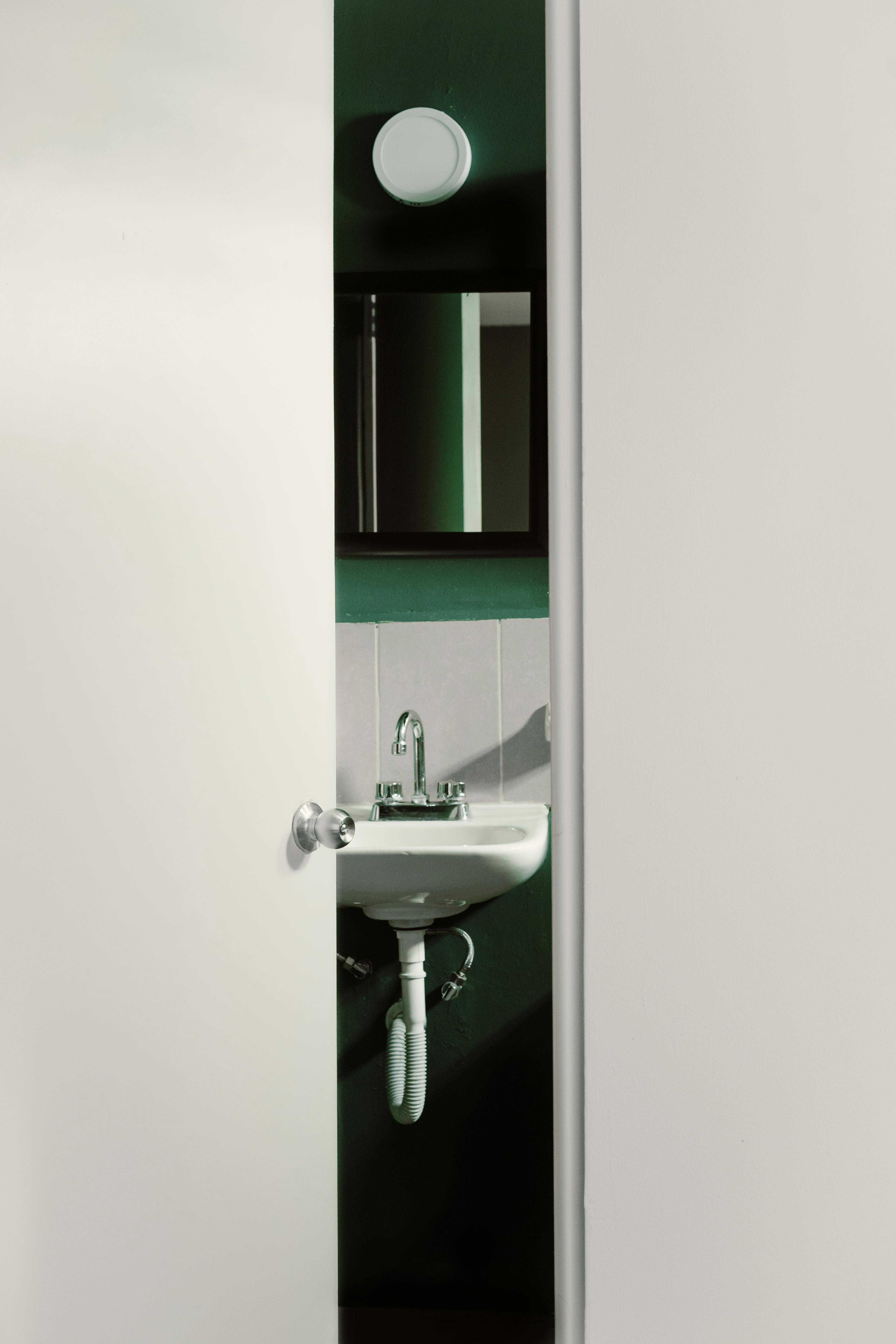 Contemporary bathroom interior with a partially open door, revealing a sleek and modern sink design.