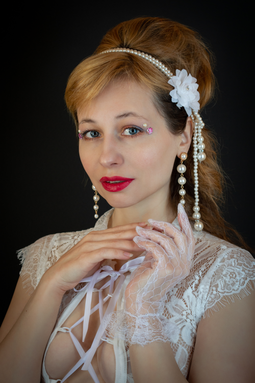 Free Portrait of a woman in lace with pearls and bright makeup set against a black background. Stock Photo
