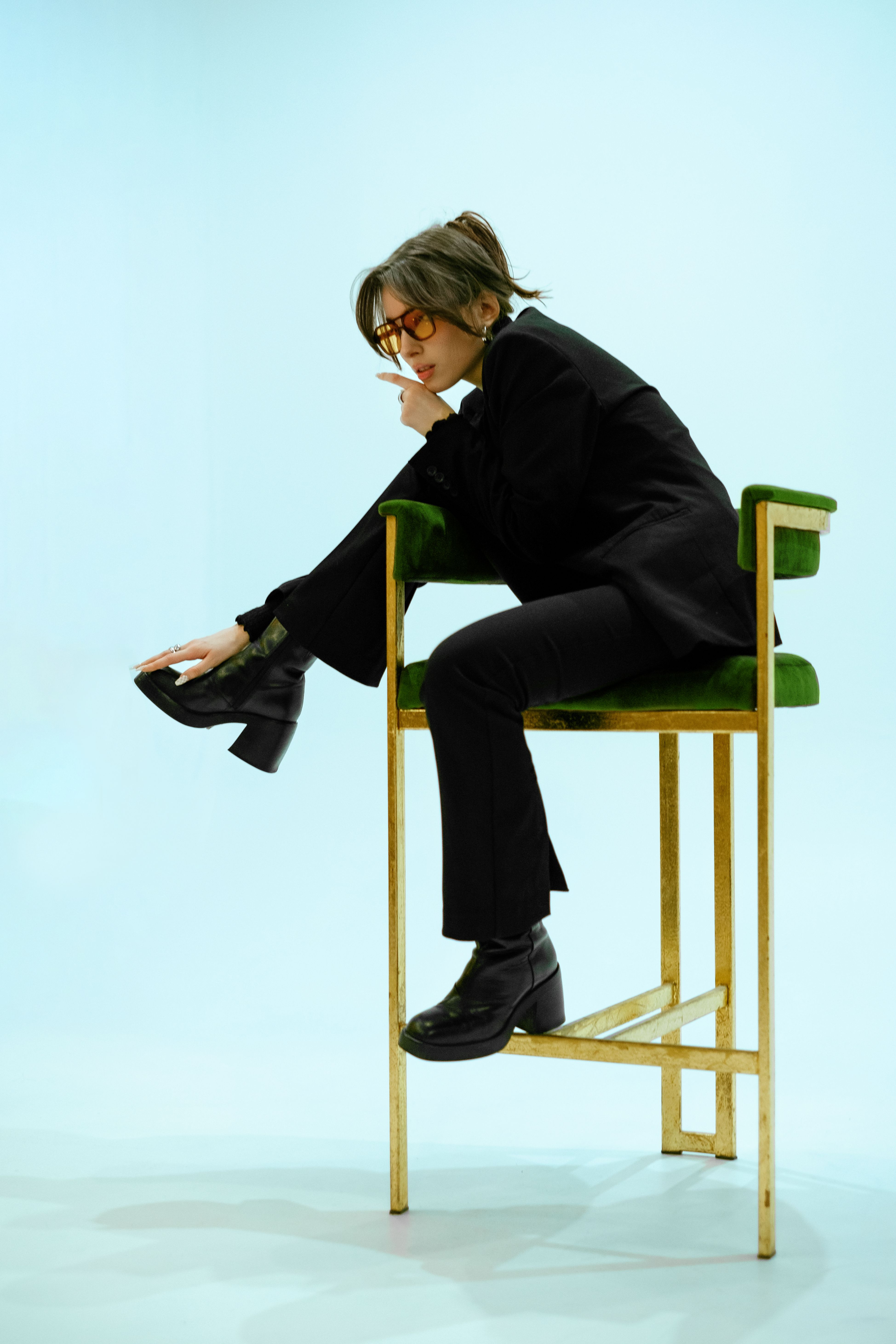 Portrait of a businesswoman in formalwear, sitting on a high chair in a studio setting.