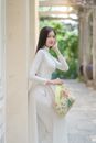 Woman in White Sleeveless Dress Holding White and Yellow Floral Handbag