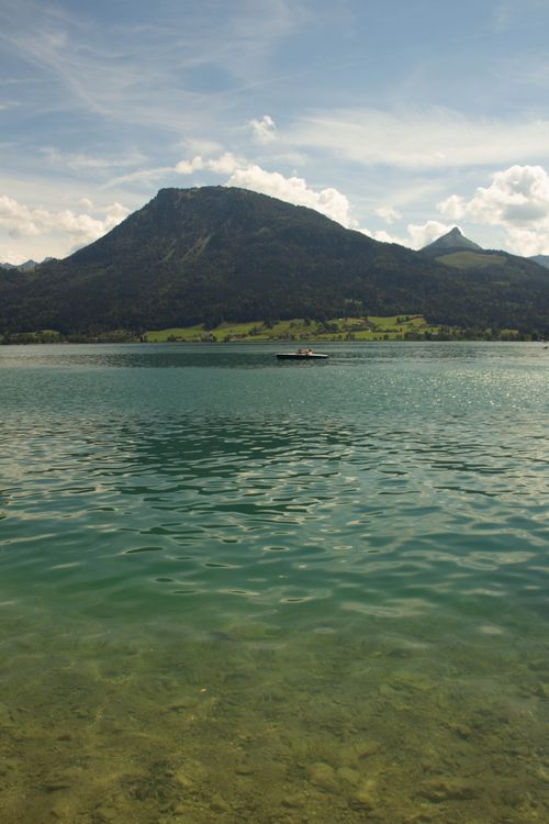 Free A tranquil scene of a mountain and lake with a small boat. Stock Photo