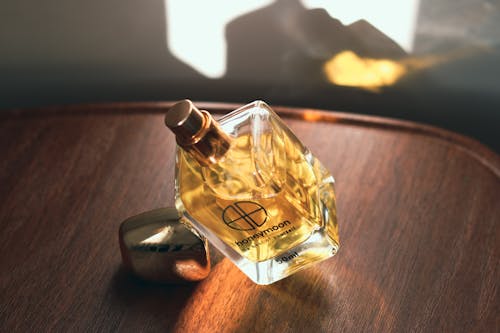 Close-Up Shot of a Glass Perfume Bottle on Wooden Surface
