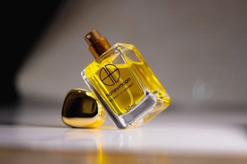 Close-Up Shot of a Glass Perfume Bottle on White Surface
